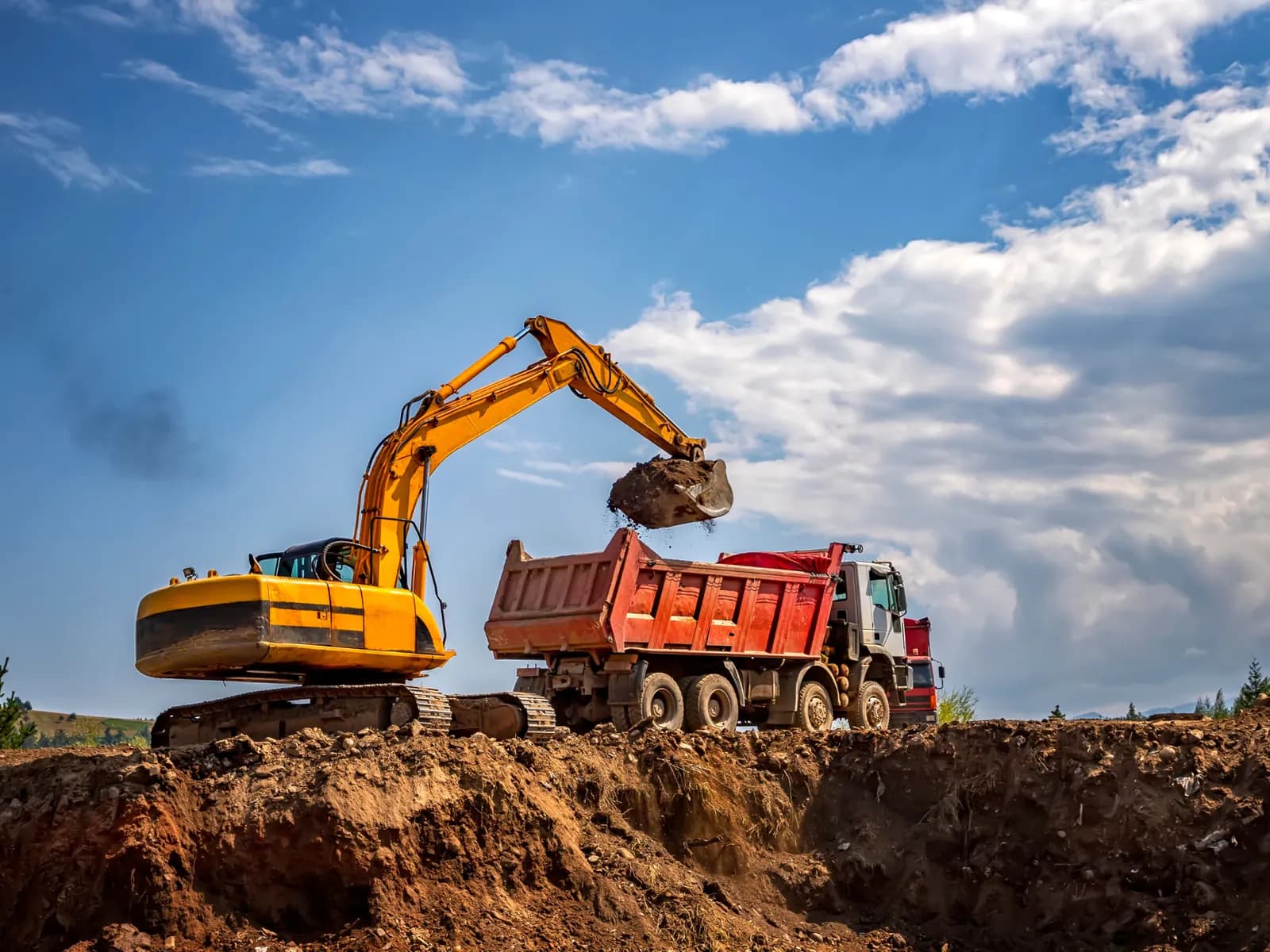 Excavadora cargando un camión de volteo durante el movimiento de tierras de una obra
